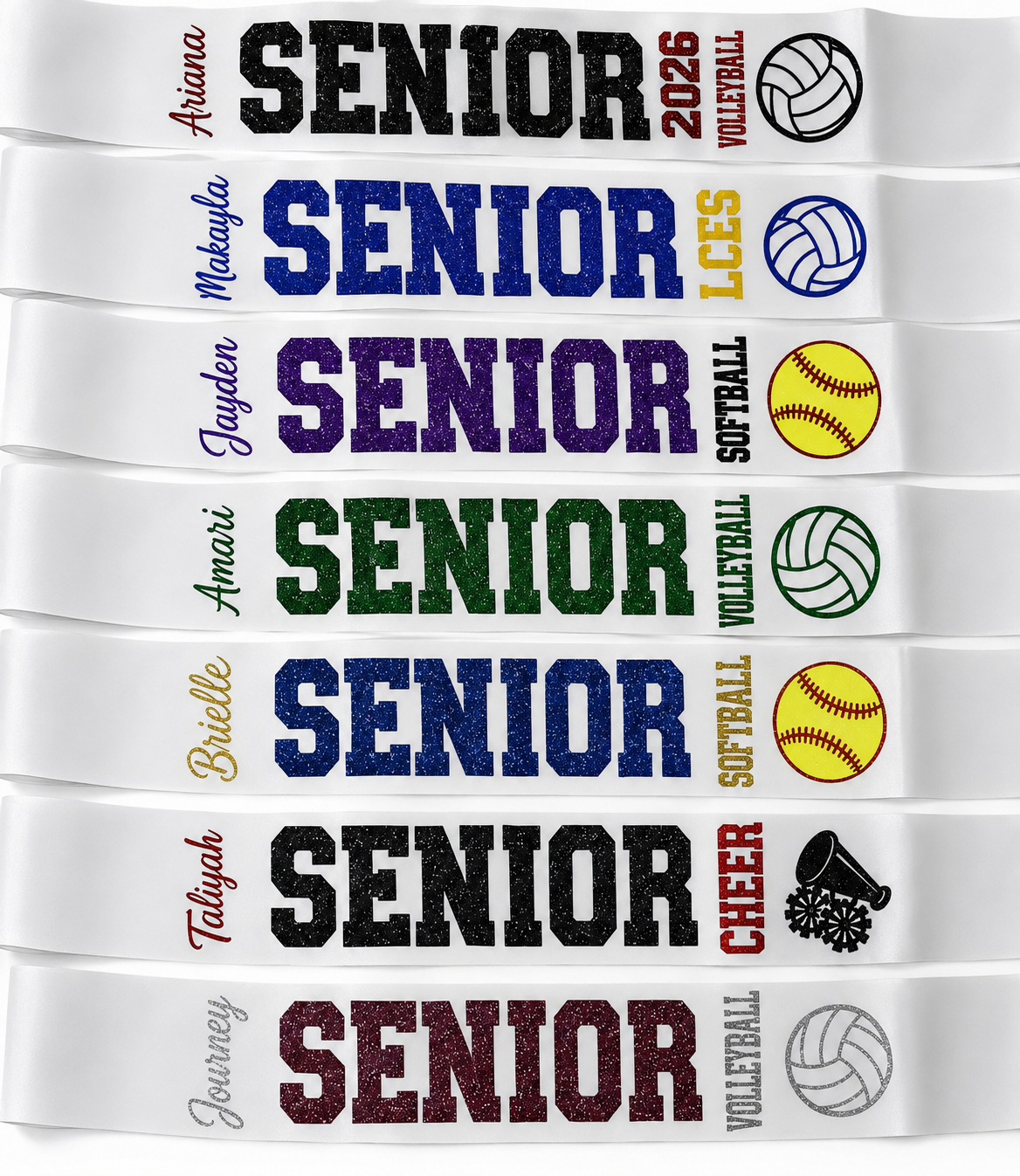A stack of white ribbed wristbands featuring customizable text and sports graphics. The wristbands display 'SENIOR' in various colors (black, blue, purple, green, gold, maroon) alongside sports icons for volleyball, softball, and basketball, with placeholder names like 'Ariana' and 'Jayden'.